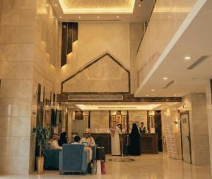 un groupe de personnes assises à des tables dans un hall dans l'établissement رتاج إن, à Al Khansāk