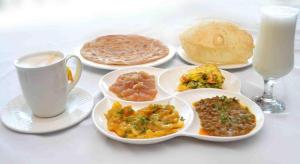 a table with plates of food and a cup of milk at Hotel White Palace Clifton in Karachi