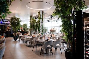 Un restaurante con mesas, sillas y plantas. en Hotel Egerkingen, idealer Zwischenstopp, en Egerkingen