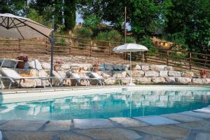 a swimming pool with chairs and an umbrella at Rustic Country House in Smirra