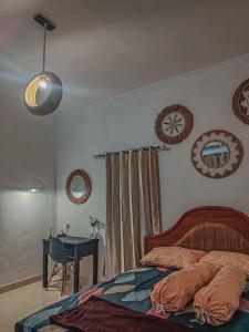 Un dormitorio con una cama y un escritorio y un reloj en la pared. en Little Loti Sikumana, en Maulafa
