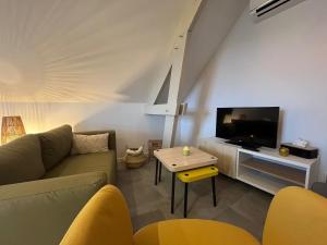 a living room with a couch and a tv and a table at L'Escale Champenoise - independent accommodation in Hautvillers