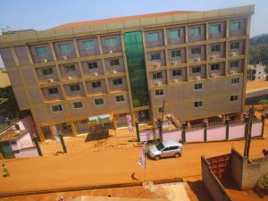 Un gran edificio con un coche aparcado delante. en Hotel Mirador Bafoussam, en Bafoussam