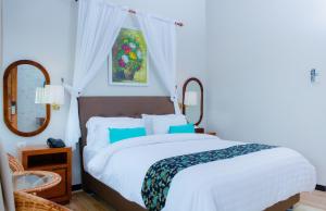 a bedroom with a large white bed with blue pillows at Bintan Exotica Resort By WH - Free Breakfast in Berakit