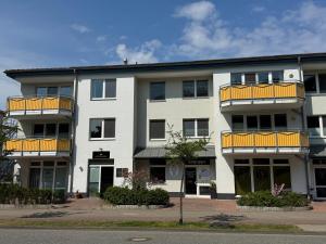 a white building with yellow balconies on a street at Ferienwohnung Quartier18-09 strandnah in Karlshagen