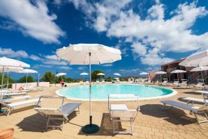une piscine avec des chaises et un parasol dans l'établissement Residence Rocce Rosse, à Isola Rossa