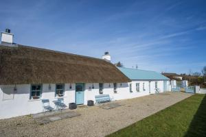 een groot wit gebouw met een rieten dak en stoelen bij Halyon Village in Greencastle