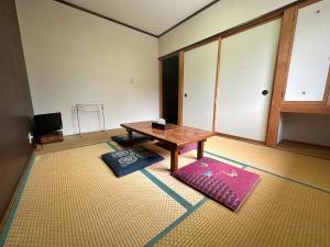 a room with a table and two mats in it at Yukiguni Base Hakuba in Hakuba