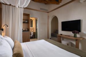 a bedroom with a bed with a television on the wall at The Yard Corfu Boutique Hotel and Spa in Moraitika