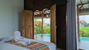 a bedroom with an open door to a pool at Rumah Tengah Sawah Bali in Ubud