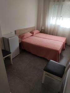 a bedroom with a bed with pink sheets and a chair at Pension La Puntica in Lo Pagán