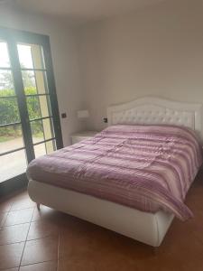 een wit bed met een paars dekbed in een slaapkamer bij Ami Affittacamere 3 in Castel San Giovanni