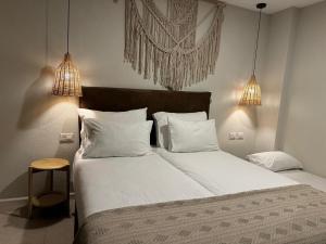 a bedroom with a large bed with white sheets and pillows at מלון המושבה כפר תבור in Kefar Tavor