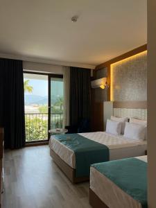 Una habitación de hotel con dos camas y balcón. en Rizom Beach Hotel Kumluca, en Kumluca