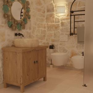 een badkamer met een wastafel, een toilet en een spiegel bij Borgo Pascarosa in Ostuni