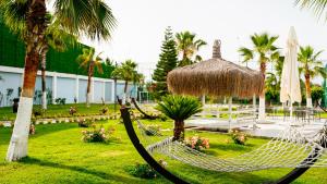 Una hamaca en un resort con palmeras y un edificio. en Rizom Beach Hotel Kumluca, en Kumluca