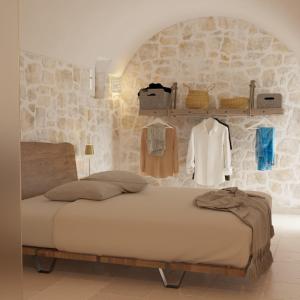een slaapkamer met een bed en een stenen muur bij Borgo Pascarosa in Ostuni
