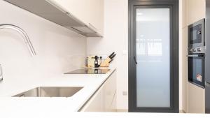 a white kitchen with a sink and a refrigerator at SUNSET SAILORS lovely apartment in Benidorm