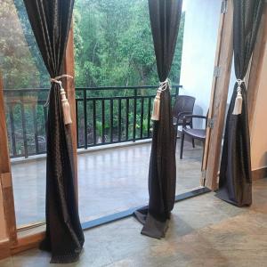 Una puerta abierta a un balcón con cortinas negras. en SL Guest House, en Mawlynnong
