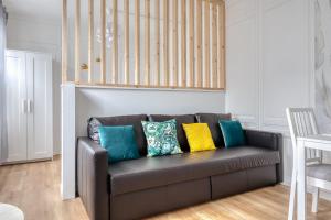 eine Couch mit bunten Kissen darauf in einem Wohnzimmer in der Unterkunft Blue Bird charmant studio avec place de parking ! in Rouen