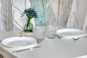 ein Tisch mit Tellern und Gläsern und einer Vase mit Blumen in der Unterkunft Blue Bird charmant studio avec place de parking ! in Rouen + 13 Fotos