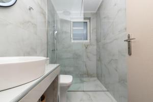 un bagno bianco con lavandino e doccia di Villa Orizzonte- First Floor Apartment a Città di Zante