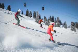 a group of three people skiing down a snow covered slope at Ellmauhof - das Generationenresort in Saalbach Hinterglemm +87 photos