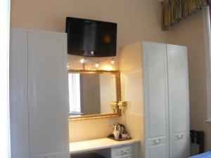 a bathroom with a mirror and a tv on a wall at Mermaid Suite Hotel in London