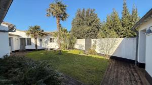 a backyard with a fence and a palm tree at Charmante maison à deux pas de la plage in Les Portes