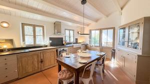 a kitchen with a wooden table and some windows at Charmante maison à deux pas de la plage in Les Portes