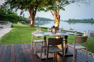 a table with wine glasses on it with a view of a river at The Xcape River Kwai in Kanchanaburi