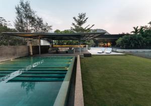 a swimming pool with a pavilion next to a yard at LohonoStays Villa Gomti in Lonavala