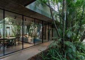 a glass house with a table and a dining room at LohonoStays Villa Gomti in Lonavala