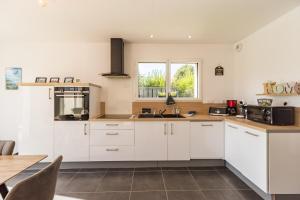 eine Küche mit weißen Schränken und einem Tisch in der Unterkunft Ty Menez - Maison neuve proche commerces et plages in Pordic