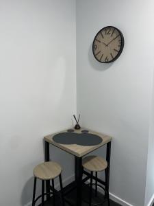 a table with two stools and a clock on a wall at Modern Studio Central WV1 Appt 4 in Wolverhampton