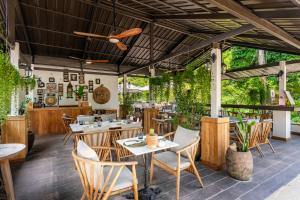 a restaurant with tables and chairs and plants at Moorea Boutique Resort Samui in Ban Tai