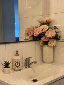 a bathroom sink with a vase of pink roses at Guildford room near Cafe and Train in Guildford