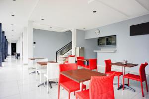 a dining room with red chairs and tables at OYO 94785 Diana Homestay Syariah in Sunggal
