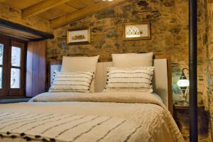 a large bed in a room with a stone wall at Casa do Talasnal by Refúgio ao Luar in Talasnal