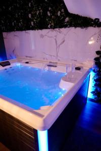 Saint-Yzan-de-SoudiacJungle Room et Jacuzzi的蓝色灯光的客房内的按摩浴缸