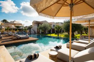an image of a swimming pool with lounge chairs and umbrellas at The Yard Corfu Boutique Hotel and Spa in Moraitika