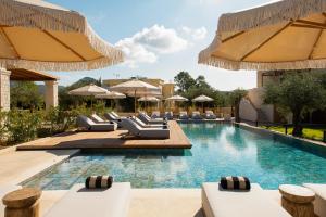 a pool with lounge chairs and umbrellas at a resort at The Yard Corfu Boutique Hotel and Spa in Moraitika