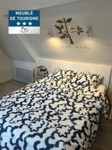 a bedroom with a bed with a black and white comforter at Appartement Duplex -Vue sur mer- à 100 m de la plage in Le Portel