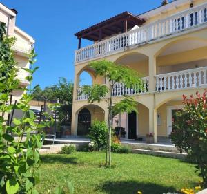 a building with a balcony and a tree in the yard at Apartment Magdalena in Sveti Filip i Jakov