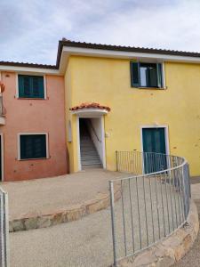 a yellow house with a gate in front of it at Blu Marlin Apartment in Santa Maria Coghinas