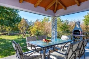 a patio with a table and chairs and a grill at Villa Kalac, a charming holiday pool oasis near the sea in Raša
