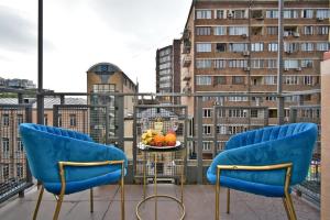 a balcony with two blue chairs and a bowl of fruit at tumanyan 38 guest hause in Yerevan