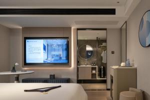 Huanman Hotel Changsha Wuyi Square South Gate Metro Station Branch في تشانغشا: غرفة فندق مع سرير وتلفزيون