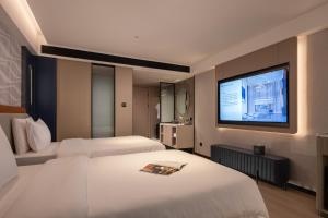 Huanman Hotel Changsha Wuyi Square South Gate Metro Station Branch في تشانغشا: غرفة فندق بها سريران وتلفزيون بشاشة مسطحة