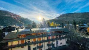 a building in a village with mountains in the background at Appartamento Cristallo - Affitti Brevi Italia in Bardonecchia